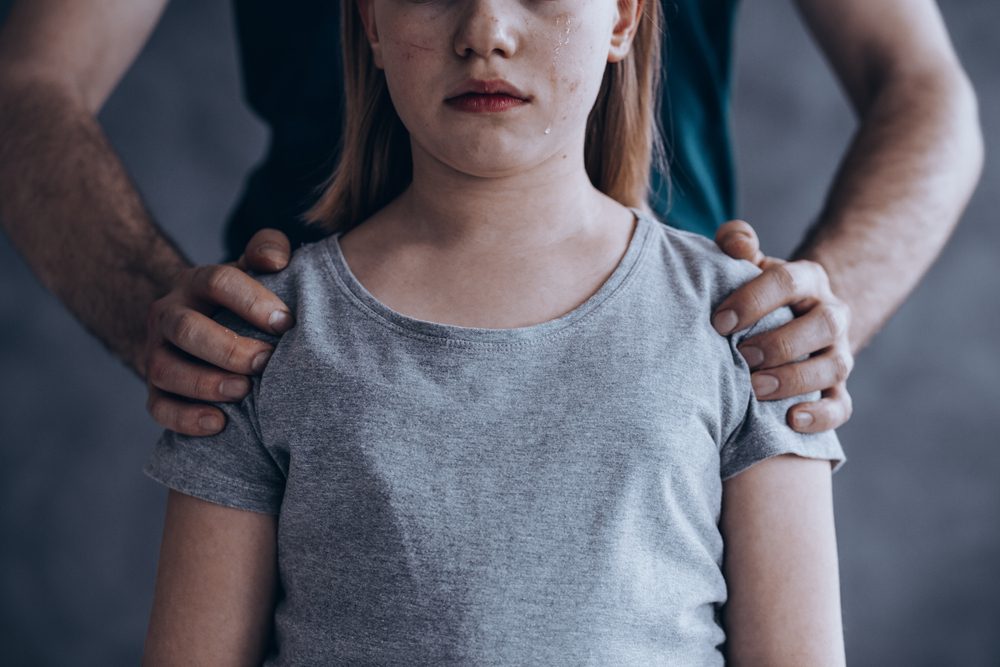 Male hands on little crying girl, concept of children exploitation
