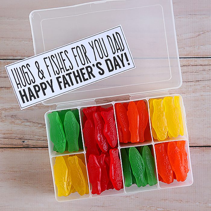 Box holds colorful gummy fish, organized by color, with a Father's Day card saying â€œHugs & Fishes for You Dad. Happy Fatherâ€™s Day!â€ resting on top.