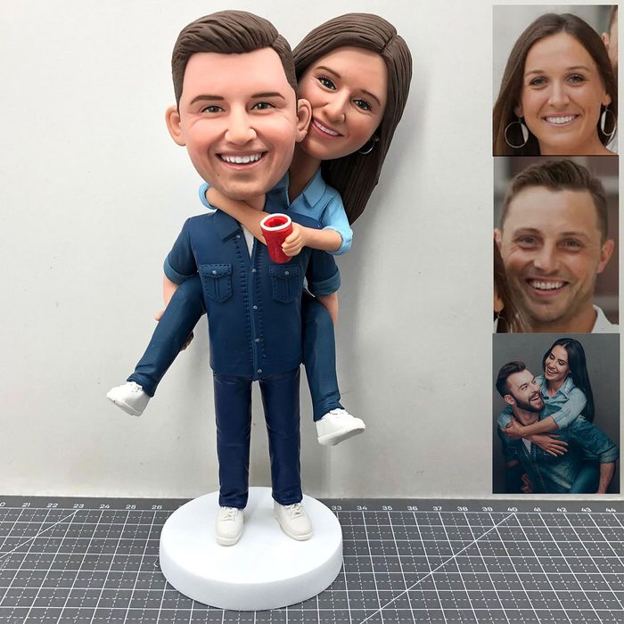 Figurine duo gives piggyback ride, smiling broadly, holding red cup; gray background and cutouts showing corresponding faces.