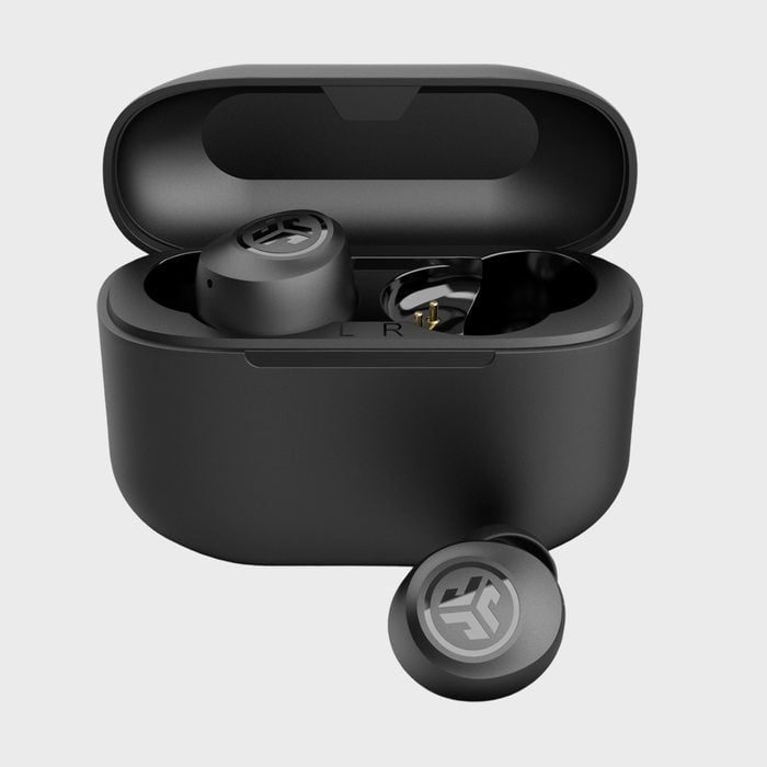 Black wireless earbuds rest in an open charging case, one earbud outside, against a plain grey background.