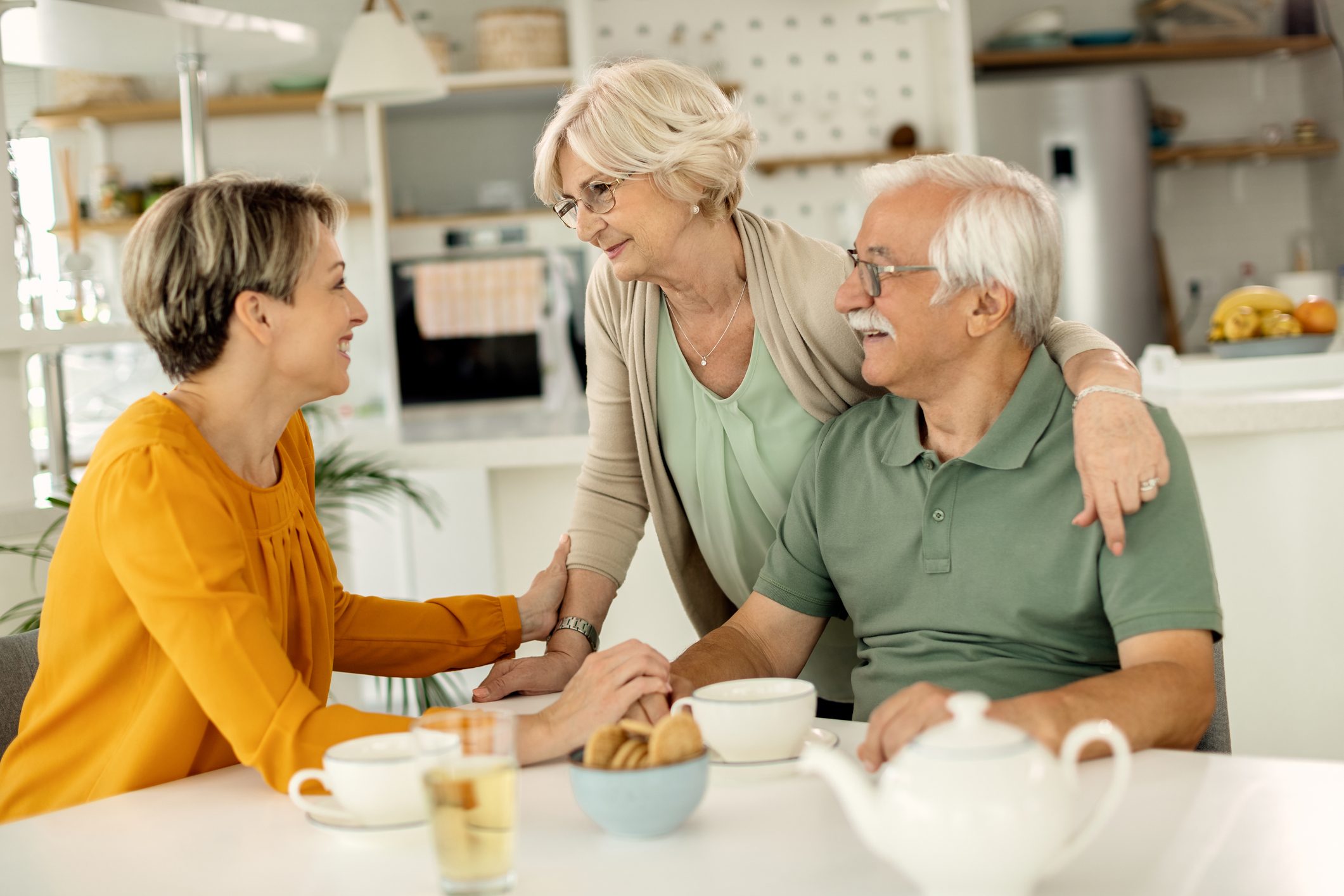 Happy mature couple talking to their adult daughter at home.