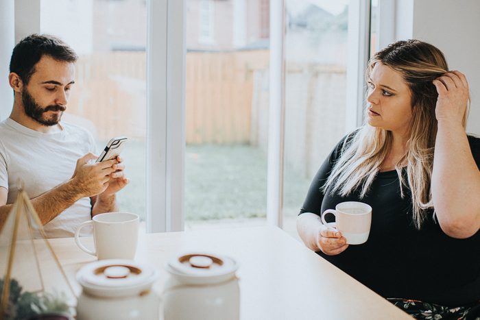 A woman looks insecure as her partner ignores her to look at his phone