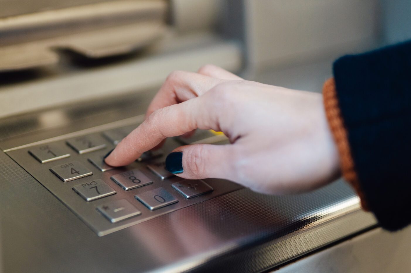 Close up of female hand entering password on keypad at automatic teller machine (ATM)