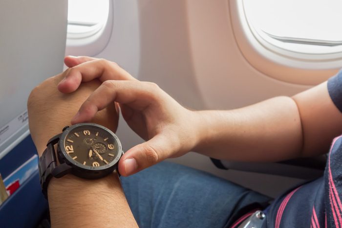 The man looking to the watch on the airplane