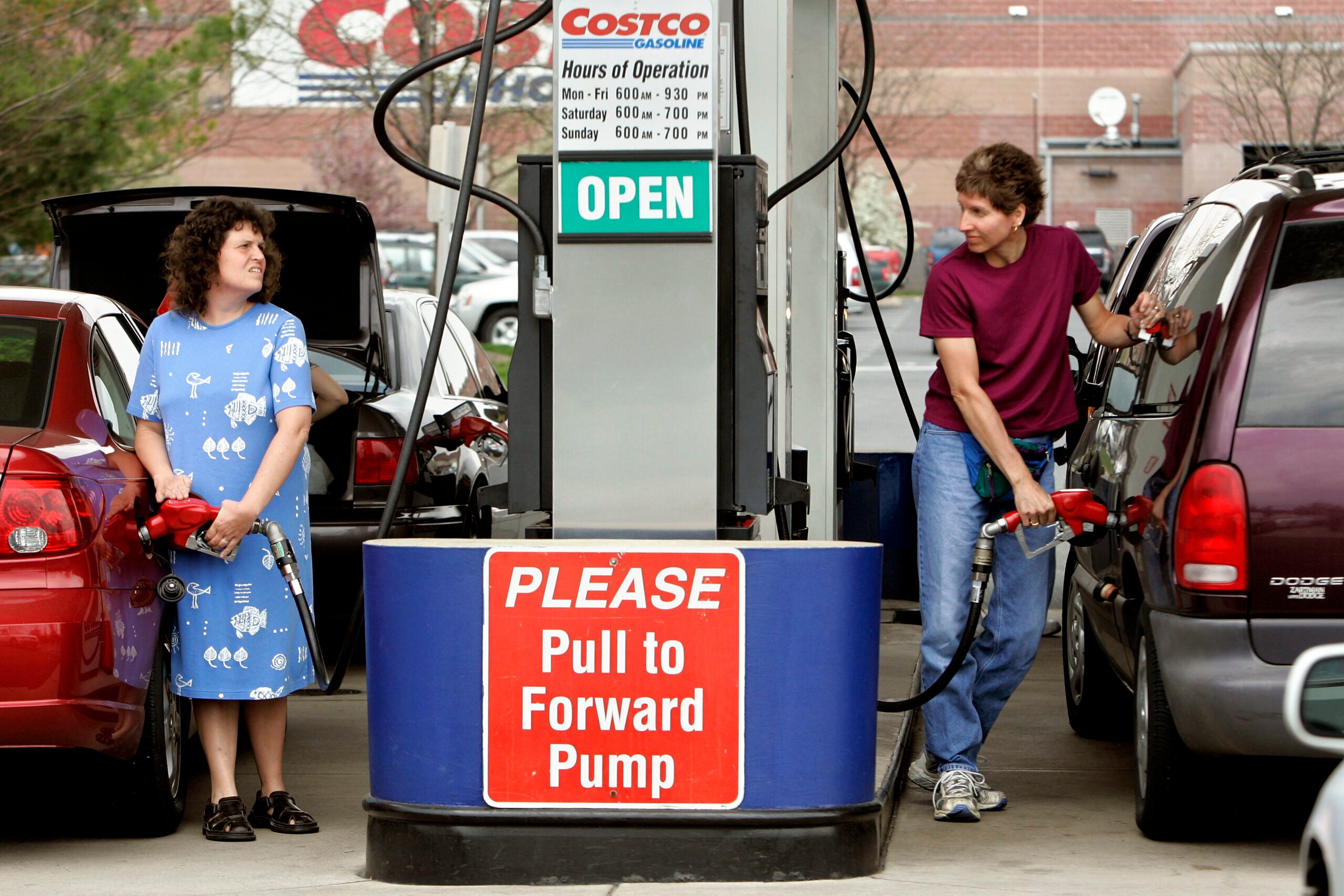 Two people on opposite sides of a Costco gas pump