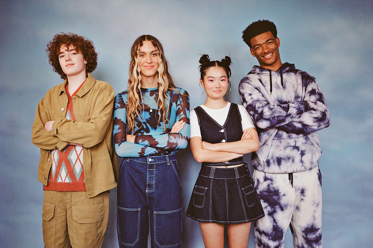 Portrait of smiling multiracial male and female friends standing with arms crossed against colored background