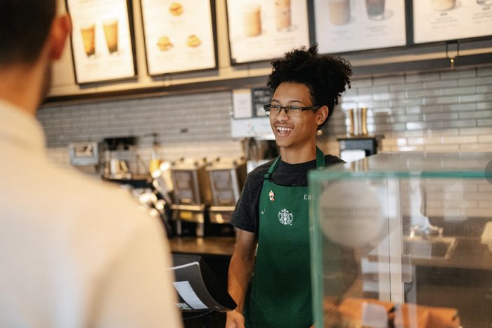 Starbucks employee smiling infront of customer