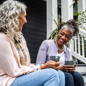 Senior women having coffee in front of suburban home