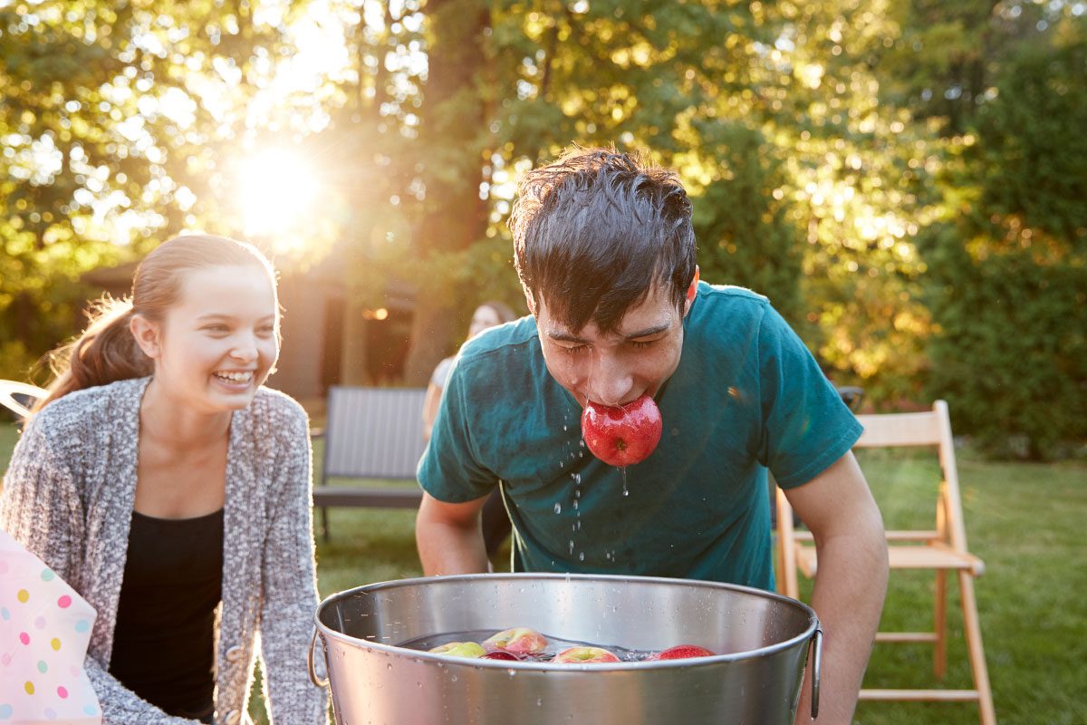 Teenage boy, apple in mouth, apple bobbing at garden party